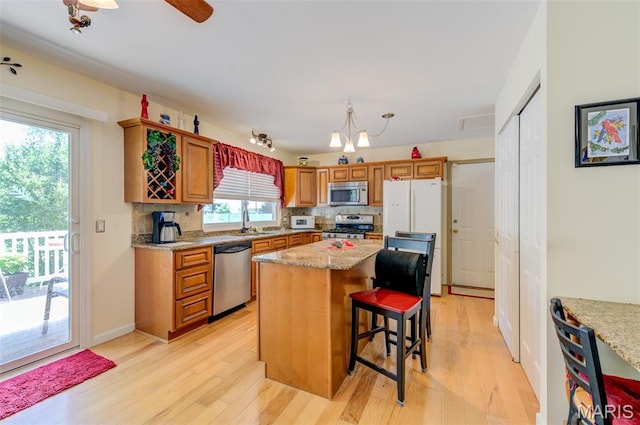 6 Barkwood Ct, Saint Peters, MO 63376 - kitchen featuring appliances with stainless steel finishes, tasteful backsplash, light wood-type flooring, brown cabinetry, and light stone counters