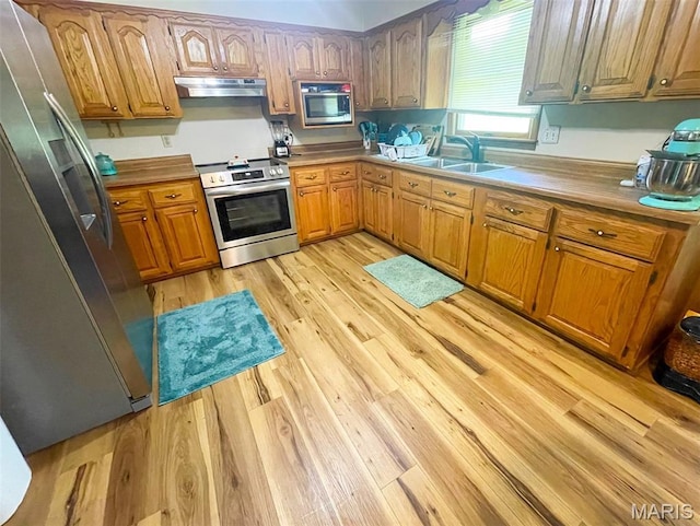 402 N Viola St, Bloomfield, MO 63825 - kitchen featuring appliances with stainless steel finishes, under cabinet range hood, light wood-type flooring, brown cabinets, and light countertops