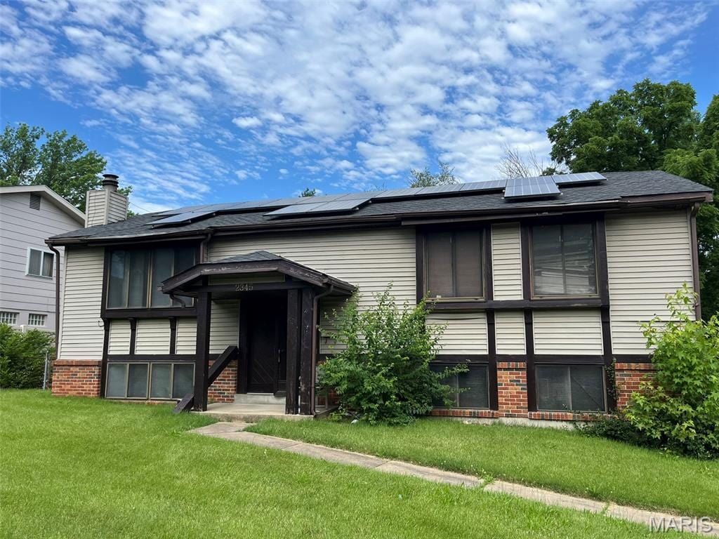 2345 Derhake Rd, Florissant, MO 63033 - view of front facade with a front lawn, solar panels, and brick siding