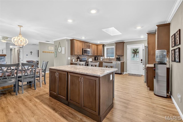 11178 Catatoga Dr, Plainview, IL 62685 - kitchen with crown molding, stainless steel appliances, a kitchen island, a skylight, and tasteful backsplash