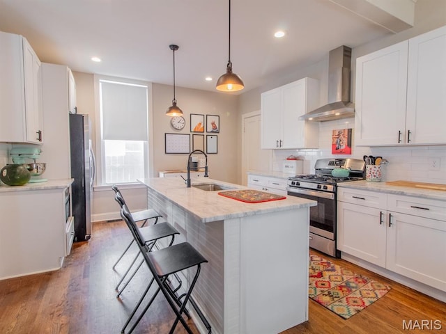 6454 Virginia Ave, Saint Louis, MO 63111 - kitchen featuring appliances with stainless steel finishes, wall chimney range hood, light wood-type flooring, decorative backsplash, and white cabinetry