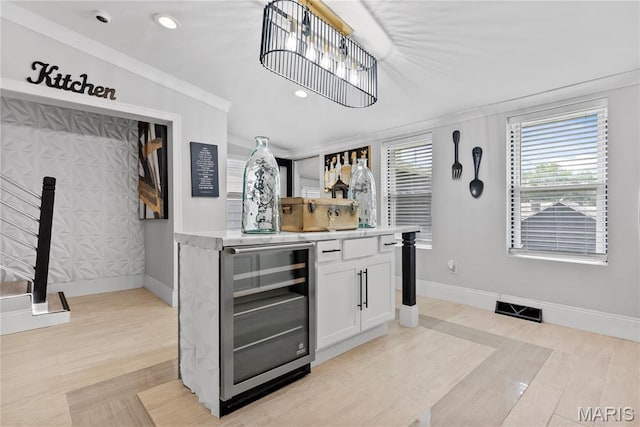 1821 Edwardsville Rd, Madison, IL 62060 - indoor dry bar with beverage cooler, light wood finished floors, recessed lighting, and crown molding