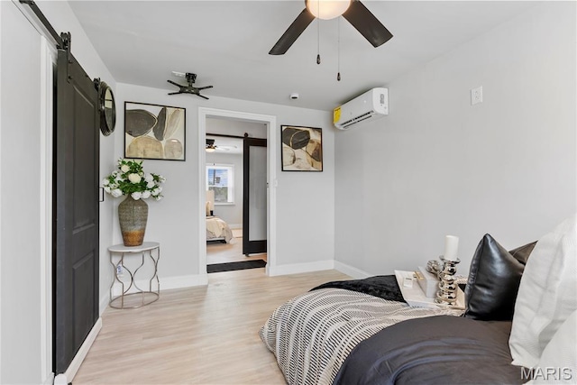 1821 Edwardsville Rd, Madison, IL 62060 - bedroom with an AC wall unit, a barn door, light wood-style flooring, and a ceiling fan