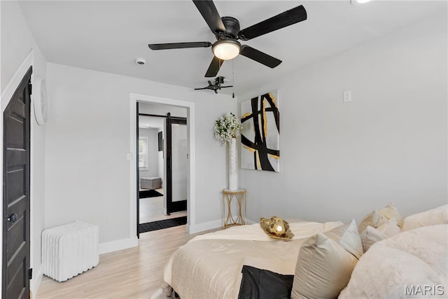 1821 Edwardsville Rd, Madison, IL 62060 - bedroom featuring a barn door, light wood-style flooring, and ceiling fan