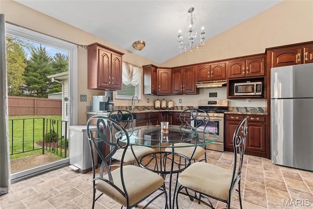 34 Windermere Dr, Glen Carbon, IL 62034 - kitchen with appliances with stainless steel finishes, under cabinet range hood, vaulted ceiling, a chandelier, and light stone finish floors