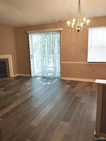 1446 Bluebird Ter, Saint Louis, MO 63144 - unfurnished dining area featuring a chandelier, wood finished floors, and a fireplace