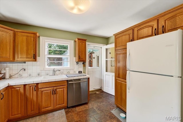 8548 Big Bend Blvd, Webster Groves, MO 63119 - kitchen featuring freestanding refrigerator, dishwasher, decorative backsplash, brown cabinets, and dark stone finish flooring