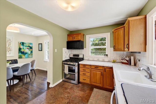 8548 Big Bend Blvd, Webster Groves, MO 63119 - kitchen featuring range with two ovens, black microwave, arched walkways, tile counters, and tasteful backsplash