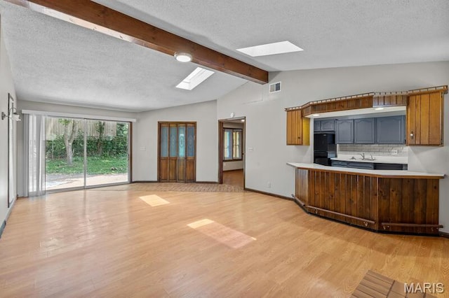 12 Country Ln, Florissant, MO 63033 - kitchen featuring a skylight, light wood finished floors, a textured ceiling, backsplash, and light countertops
