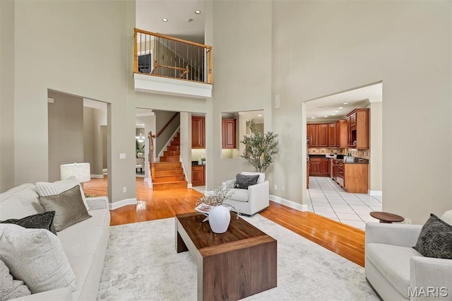 1011 Hawks Landing Dr, Lake St Louis, MO 63367 - living room featuring light wood-type flooring, stairway, and a towering ceiling