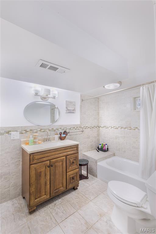 7373 Marwinette Ave, Saint Louis, MO 63116 - bathroom featuring tile walls, vanity, shower / bath combination with curtain, and tile patterned floors