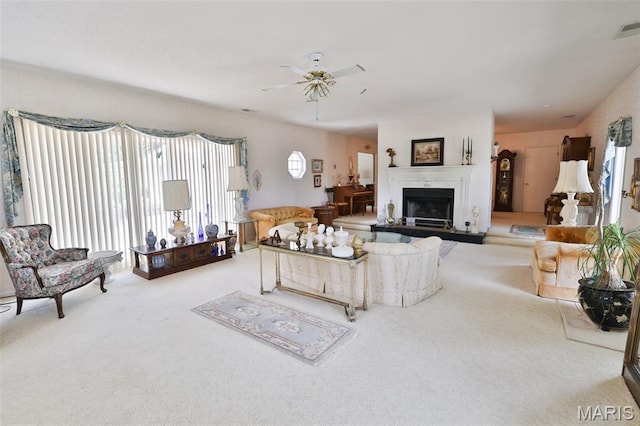 613 N W St, Raymond, IL 62560 - living room featuring carpet, a ceiling fan, and a fireplace with raised hearth