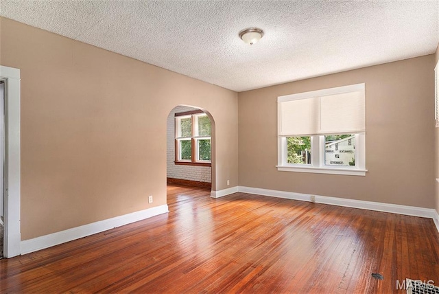 11714 Larimore Rd, Saint Louis, MO 63138 - empty room featuring arched walkways, wood-type flooring, and a textured ceiling
