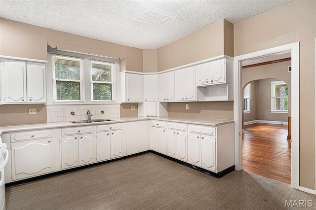 11714 Larimore Rd, Saint Louis, MO 63138 - kitchen featuring dark wood-style floors, arched walkways, white cabinetry, light countertops, and a textured ceiling