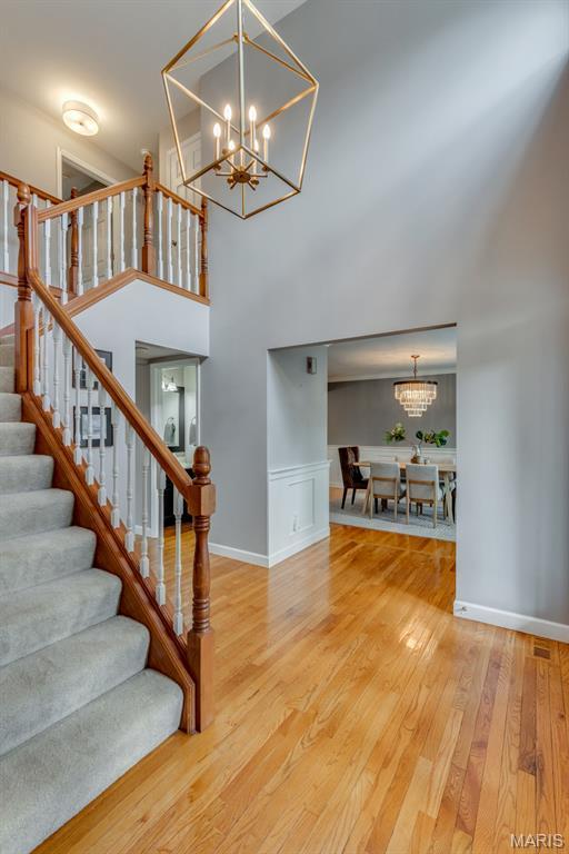 13153 Barrett Meadows Dr, Ballwin, MO 63021 - staircase with a chandelier, wood finished floors, and a high ceiling