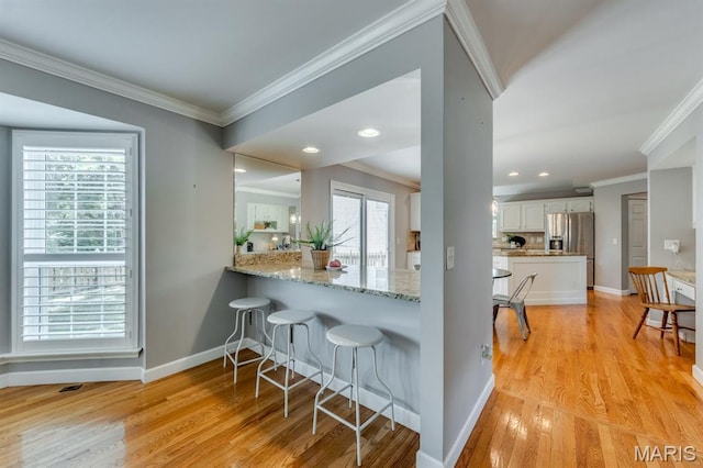 13153 Barrett Meadows Dr, Ballwin, MO 63021 - kitchen featuring white cabinetry, crown molding, stainless steel fridge, light wood-style flooring, and a kitchen bar