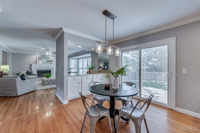 13153 Barrett Meadows Dr, Ballwin, MO 63021 - dining space featuring a ceiling fan, light wood-style flooring, a glass covered fireplace, and ornamental molding