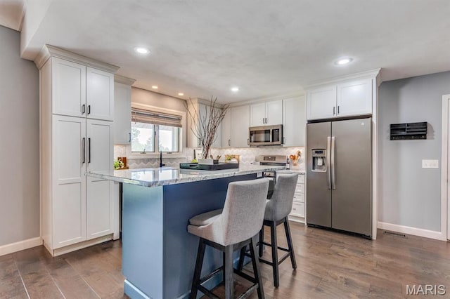 3534 Carriage Run Dr, Saint Charles, MO 63303 - kitchen featuring stainless steel appliances, a breakfast bar, white cabinets, dark wood-style floors, and recessed lighting
