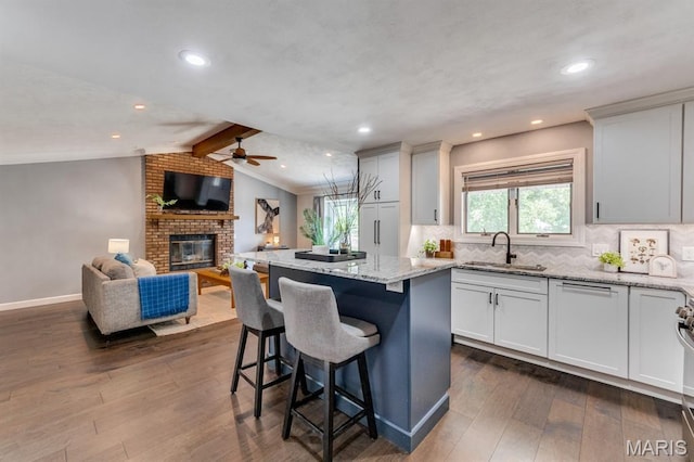 3534 Carriage Run Dr, Saint Charles, MO 63303 - kitchen featuring a ceiling fan, a kitchen island, dark wood-style flooring, light stone counters, and tasteful backsplash