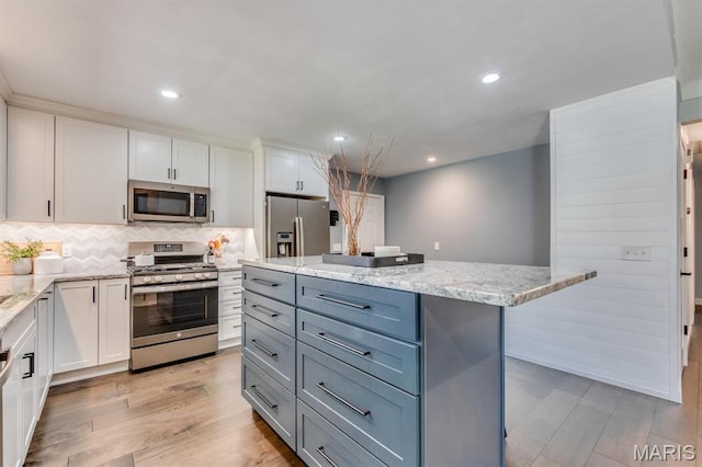 3534 Carriage Run Dr, Saint Charles, MO 63303 - kitchen featuring appliances with stainless steel finishes, white cabinetry, light wood-type flooring, decorative backsplash, and recessed lighting