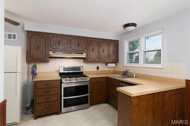 110 N 74th St, Belleville, IL 62223 - kitchen with stainless steel appliances, under cabinet range hood, light countertops, a peninsula, and tasteful backsplash
