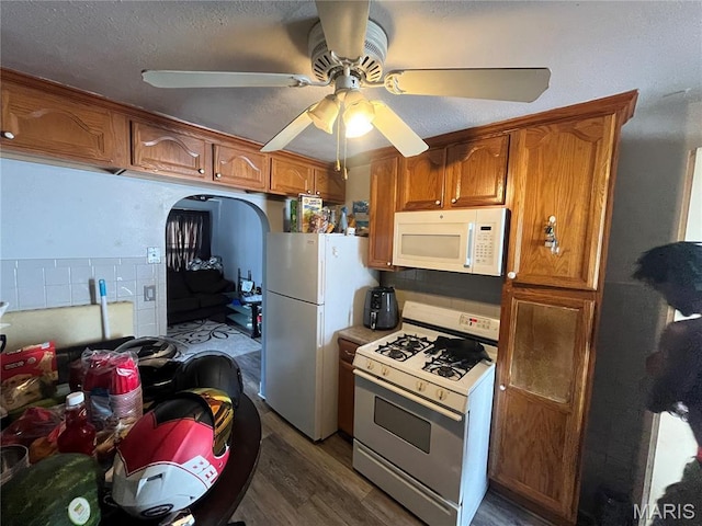 821 Center St, East Alton, IL 62024 - kitchen featuring white appliances, brown cabinetry, dark wood-style flooring, ceiling fan, and a textured ceiling