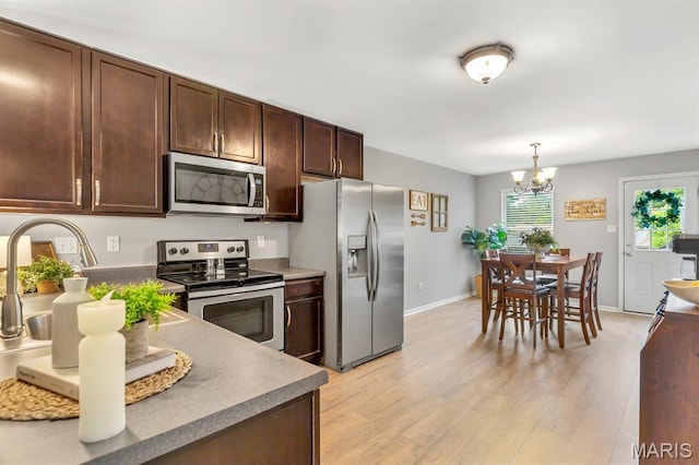 688 Rabbit Run Dr, Wentzville, MO 63385 - kitchen with appliances with stainless steel finishes, dark brown cabinets, light wood finished floors, and a chandelier
