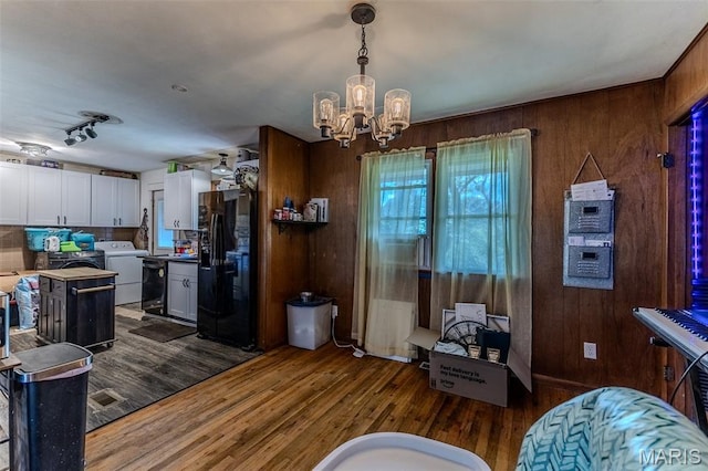 304 Warren St, Richland, MO 65556 - dining space featuring washer / dryer, a chandelier, wooden walls, and dark wood-style floors