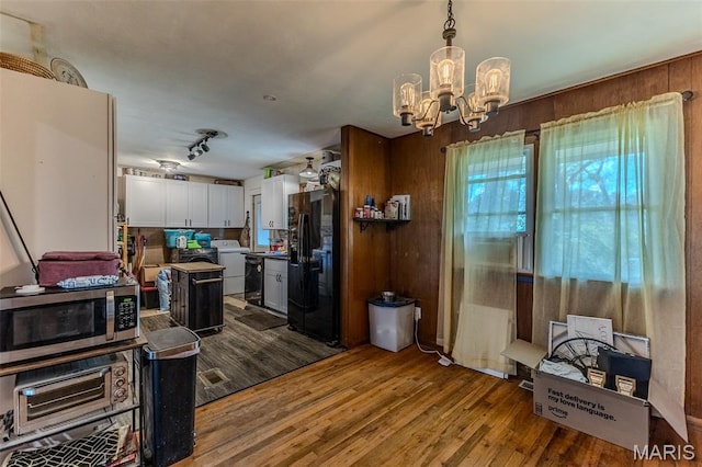 304 Warren St, Richland, MO 65556 - kitchen with black fridge, stainless steel microwave, washer / dryer, a chandelier, and white cabinets