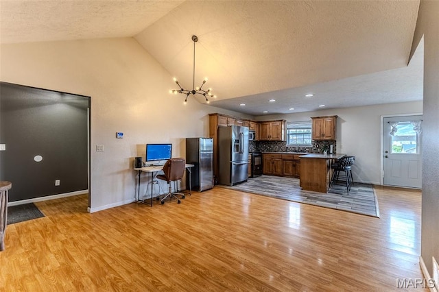 143 Lyle Curtis Cir, Waynesville, MO 65583 - kitchen featuring appliances with stainless steel finishes, brown cabinetry, light wood-style flooring, a chandelier, and tasteful backsplash