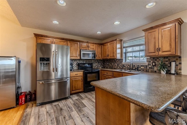 143 Lyle Curtis Cir, Waynesville, MO 65583 - kitchen featuring appliances with stainless steel finishes, brown cabinets, a peninsula, light wood-type flooring, and dark countertops