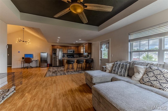 143 Lyle Curtis Cir, Waynesville, MO 65583 - living room featuring a chandelier, light wood-style flooring, a ceiling fan, and a raised ceiling