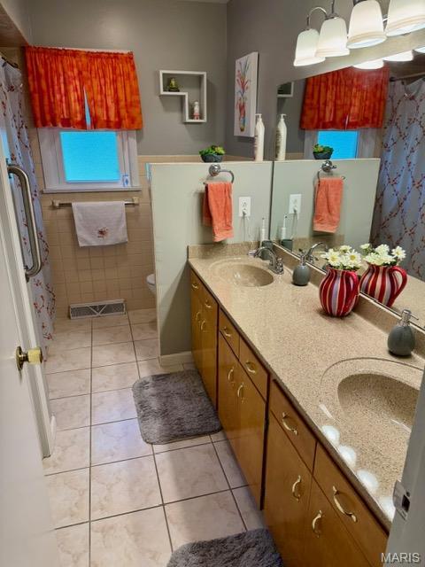 8 E 11th St, Washington, MO 63090 - bathroom featuring tile patterned flooring, double vanity, a wainscoted wall, and tile walls