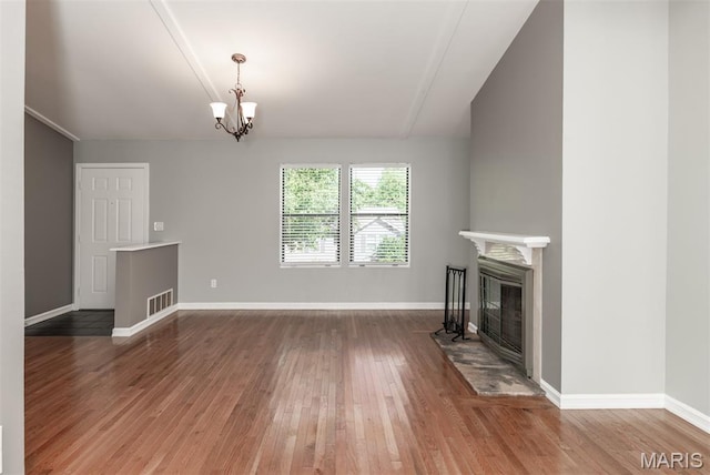 1409 Castle Mill Dr, Arnold, MO 63010 - unfurnished living room featuring hardwood / wood-style flooring, a glass covered fireplace, and a chandelier
