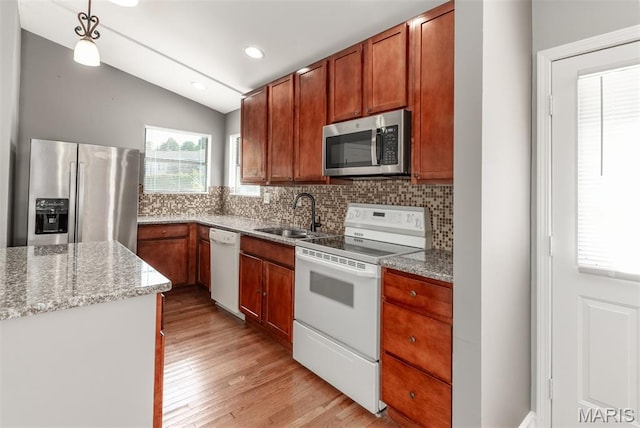 1409 Castle Mill Dr, Arnold, MO 63010 - kitchen featuring stainless steel appliances, backsplash, light wood-style floors, lofted ceiling, and light stone countertops