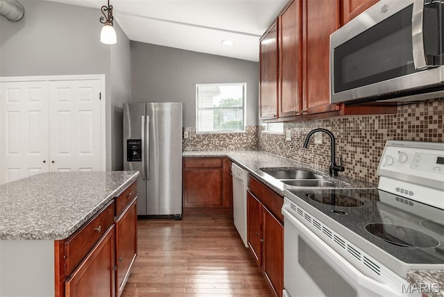 1409 Castle Mill Dr, Arnold, MO 63010 - kitchen featuring appliances with stainless steel finishes, wood finished floors, vaulted ceiling, tasteful backsplash, and light stone countertops