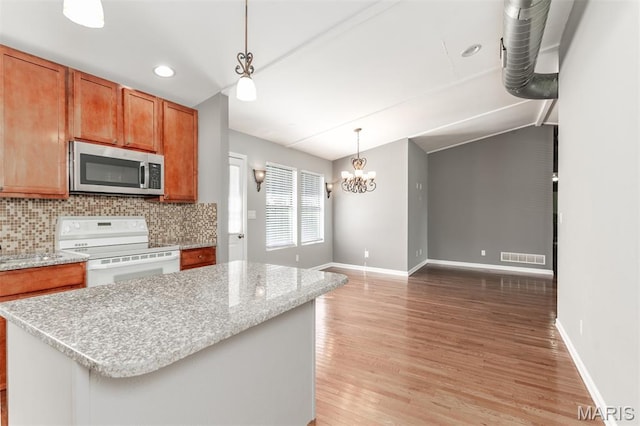 1409 Castle Mill Dr, Arnold, MO 63010 - kitchen featuring stainless steel microwave, white electric stove, light wood-style flooring, brown cabinetry, and a kitchen island