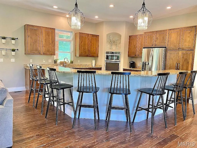 1106 Palmer Pl, Imperial, MO 63052 - kitchen featuring stainless steel appliances, brown cabinetry, dark wood-style floors, pendant lighting, and a breakfast bar area