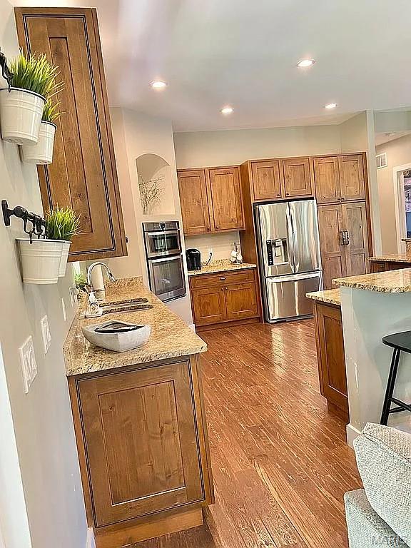 1106 Palmer Pl, Imperial, MO 63052 - kitchen featuring stainless steel fridge, brown cabinetry, dark wood-style flooring, light stone countertops, and recessed lighting