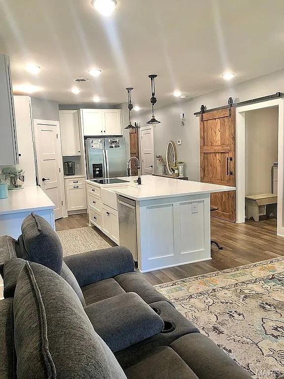 1106 Palmer Pl, Imperial, MO 63052 - kitchen with stainless steel appliances, wood finished floors, a barn door, light countertops, and white cabinetry