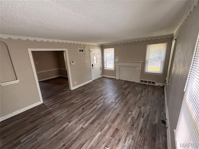6765 Kenwood Dr, Northwoods, MO 63121 - unfurnished living room featuring a textured ceiling and dark wood-type flooring