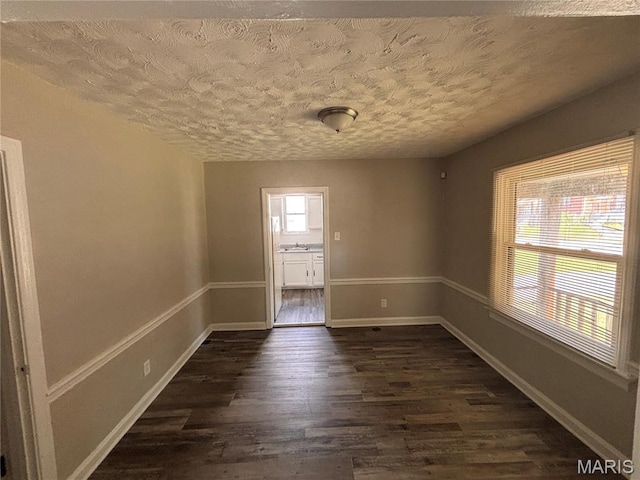 6765 Kenwood Dr, Northwoods, MO 63121 - unfurnished room with dark wood-style flooring and a textured ceiling
