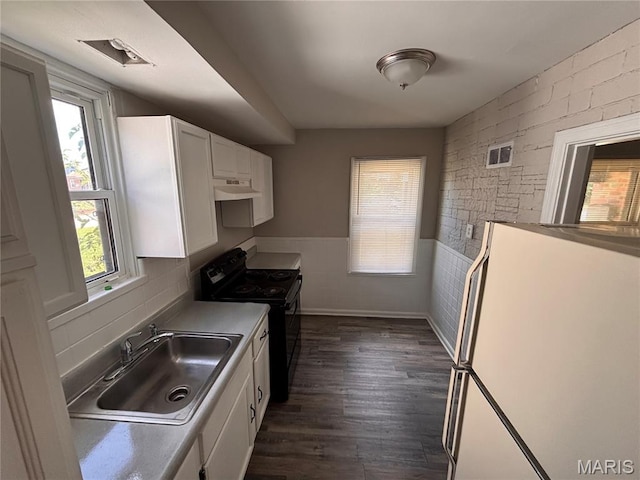 6765 Kenwood Dr, Northwoods, MO 63121 - kitchen featuring black range with electric stovetop, white cabinets, freestanding refrigerator, dark wood-style floors, and wainscoting