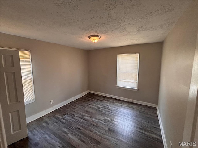 6765 Kenwood Dr, Northwoods, MO 63121 - spare room featuring dark wood-style flooring and a textured ceiling