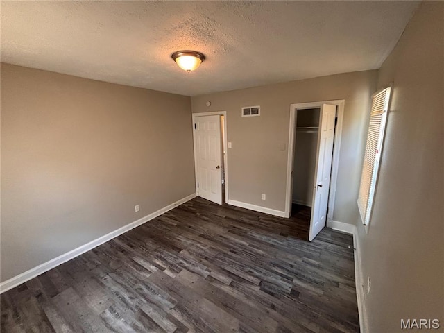 6765 Kenwood Dr, Northwoods, MO 63121 - unfurnished bedroom with dark wood-style flooring, a textured ceiling, and a closet