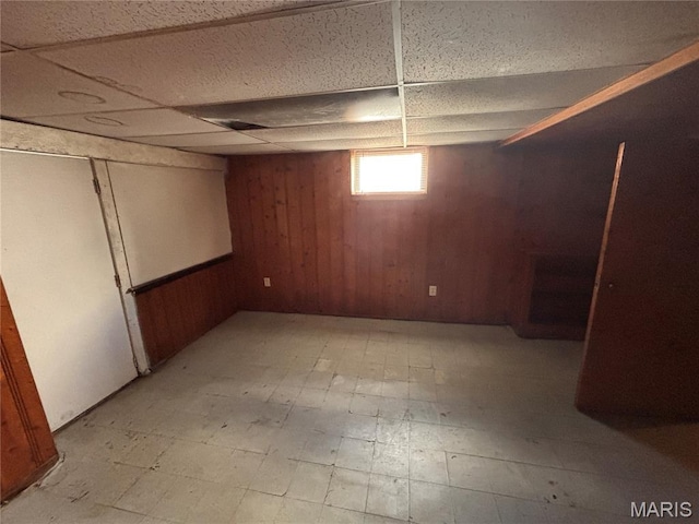6765 Kenwood Dr, Northwoods, MO 63121 - basement featuring light floors, wood walls, and a drop ceiling