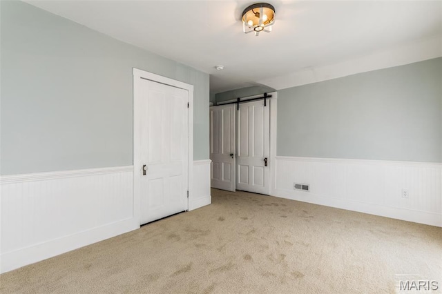 712 Maple St, Hillsboro, MO 63050 - unfurnished bedroom featuring a wainscoted wall, carpet flooring, and a barn door