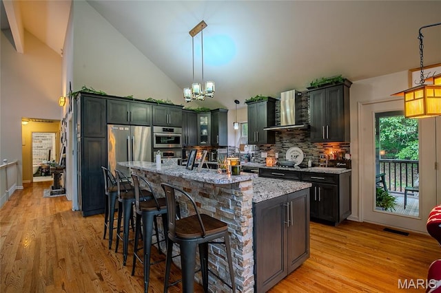 532 Fairfield Valley Rd, Pacific, MO 63069 - kitchen featuring light stone counters, high vaulted ceiling, wall chimney exhaust hood, tasteful backsplash, and appliances with stainless steel finishes
