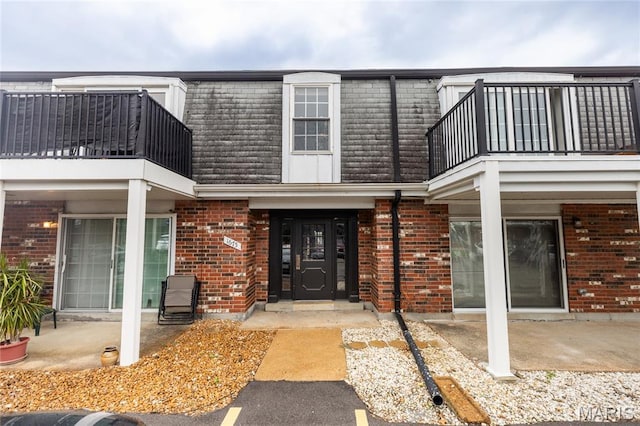 1675 Blue Ridge Dr Unit B, Lemay Township, MO 63125 - property entrance featuring a balcony, mansard roof, brick siding, and a patio area