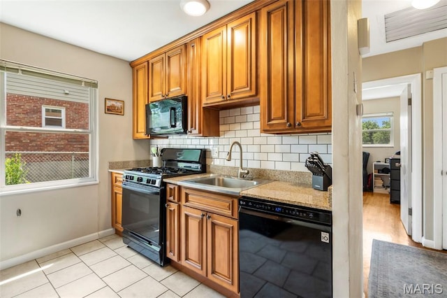 346 Madison Ave, Saint Louis, MO 63119 - kitchen with black appliances, backsplash, brown cabinets, light tile patterned floors, and light stone counters